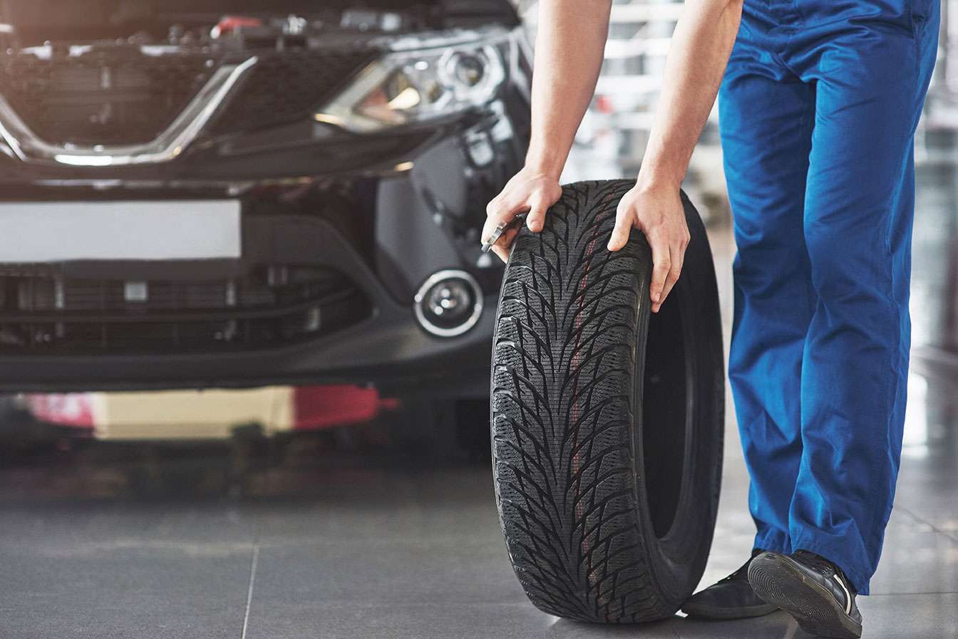 technician-with-blue-workwear-holding-wrench-tire-while-showing-thumb-up